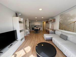 sala de estar con sofá blanco y TV de pantalla plana en Alquilaencanarias El Faro Beach, en El Médano