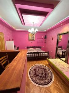 Pokój z różowymi ścianami, stołem i łóżkiem w obiekcie Villa Old Town w mieście Podgorica