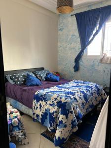 Schlafzimmer mit einem Bett mit blauer und weißer Bettwäsche in der Unterkunft Très belle appartement agadir in Agadir