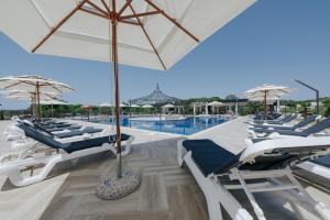 a pool with chairs and umbrellas next to a pool at Family Resort in Ulcinj