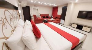 a bedroom with a large bed with red and white pillows at Hotel Mairona Gulberg Lahore in Lahore