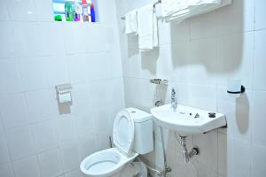 a white bathroom with a toilet and a sink at THE PINGS BNB in Narok
