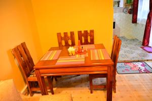 a dining room table with three chairs and a yellow wall at THE PINGS BNB in Narok
