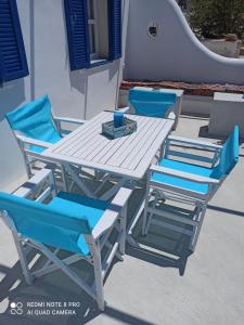a white picnic table and chairs with blue cushions at Vlastos 2 in Mylopotas