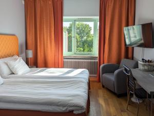 Habitación de hotel con cama, escritorio y TV. en Hotell Kristina en Sigtuna