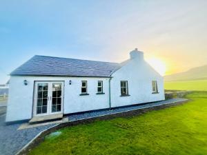 a white house with a sunset in the background at Dunnaglea Cottage, Ballintoy in Ballintoy
