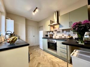 a kitchen with white appliances and a black counter top at The Lily•Central Beeston•Private Apartment•SmartTV•Free Wi-Fi•Tram• in Nottingham