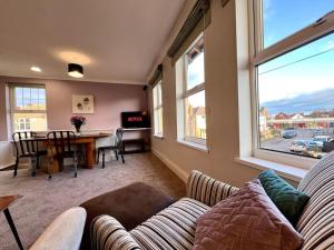 a living room with a couch and a table and windows at The Lily•Central Beeston•Private Apartment•SmartTV•Free Wi-Fi•Tram• in Nottingham