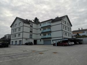 a large white building with cars parked in a parking lot at Apartma Elton in Gornja Radgona