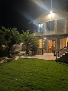 una casa con palmeras delante de ella por la noche en The Farmerian Resort, en Belparāo