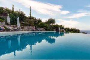 uma piscina com água azul e guarda-sóis em Villa Ionia with pool and sea view em Gaios