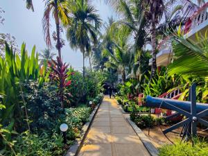 a walkway through a tropical garden with palm trees at Vintage Beach Resort in Agonda