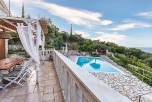 uma varanda com uma piscina, uma mesa e cadeiras em Villa Ionia with pool and sea view em Gaios