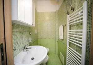 un bagno piastrellato verde con lavandino e servizi igienici di Casa di Alice By Vivimy a Gallipoli Altre 25 foto