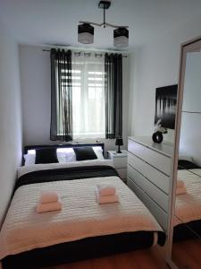 a bedroom with two beds and a dresser at Apartament Mickiewicza w centrum Augustowa in Augustów
