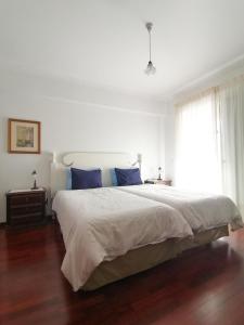 フンシャルにあるApartament Ladeira Centroの白いベッドルーム(青い枕の大型ベッド付)