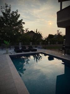 a swimming pool with chairs and a sunset in the background at Villa Sunrise in Sarajevo