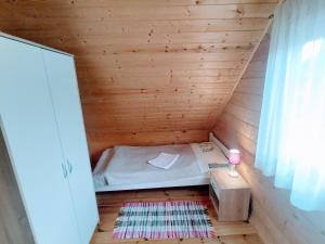 a small room with a bed in a wooden cabin at Domek Nad Zatoką in Giżycko