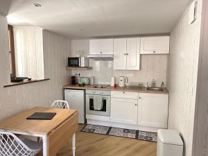 a kitchen with white cabinets and a wooden table at Duplex en ville vue château - Studio - Parking in Kaysersberg