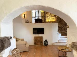 ein Wohnzimmer mit einem Torbogen mit einem Sofa und einem TV in der Unterkunft Casa Olene - 400 year old Mill in Mijas Pueblo in Málaga