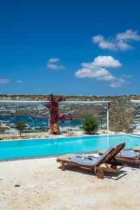 a swimming pool with two lounge chairs next to a building at Sea View Villa in Ornos in Ornos