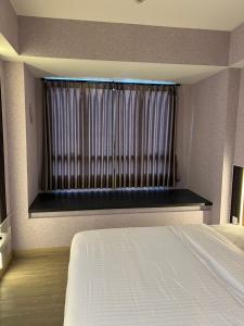 um quarto com uma cama e uma janela com cortinas em Newly renovated apartement @ collins boulevard em Warungmangga