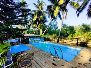 a resort pool with chairs and palm trees at Vintage Beach Resort in Agonda