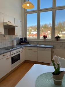 una cucina con mobili bianchi, finestre e tavolo di Ferienwohnung - Toscanapark a Gmunden