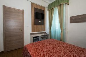 ミラノにあるホテル ピオラのベッドとテレビが備わるホテルルームです。