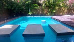 a swimming pool with blue water and benches in it at Meno Island Villas in Gili Meno