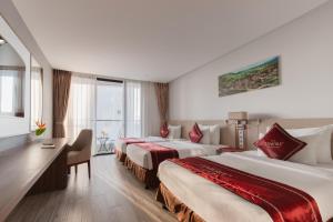 a hotel room with two beds and a desk at LeMore Hotel Nha Trang in Nha Trang