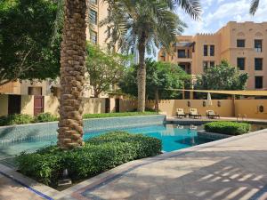 a swimming pool with a palm tree next to a building at PALACE DOWNTOWN APARTMENT in Dubai