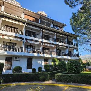 ein großes weißes Gebäude mit Balkonen und Büschen in der Unterkunft Apartamento Parque Gredos in Arenas de San Pedro