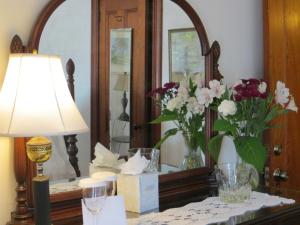 a table with a lamp and flowers in a mirror at Atlantic Ark Inn in Boothbay Harbor