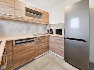 een keuken met houten kasten en een roestvrijstalen koelkast bij RAJ Living - 2 Zimmer Wohnungen mit Balkon - 25 Min zur Messe DUS in Heiligenhaus