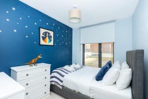a blue bedroom with a bed and a dresser at Modern 2BR wPatio & free parking, Canning Town in London