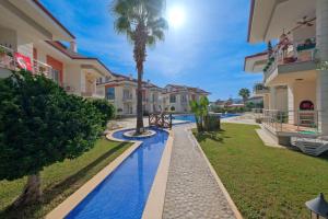 a villa with a swimming pool and a palm tree at Körfez Garden Apartments in Fethiye