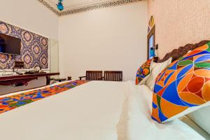ein Schlafzimmer mit einem großen weißen Bett mit bunten Kissen in der Unterkunft FabHotel Ambika Chirwa House in Udaipur