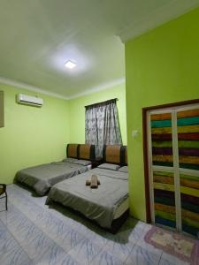 - 2 lits dans une chambre aux murs verts dans l'établissement Perhentian Idaman, aux Îles Perhentian