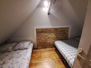 um quarto no sótão com 2 camas e uma parede de tijolos em Atypique et douillet nid em Vougeot