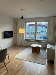 a living room with a table and a large window at Cozy apartment 2 stops-15 mins away from city center in Stockholm