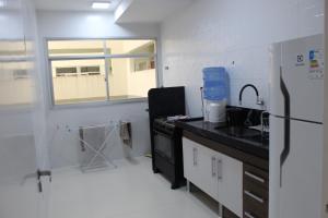 a kitchen with a sink and a refrigerator at Apt novissimo 3 quartos c elevador a 300m da orla Praia do Morro in Guarapari