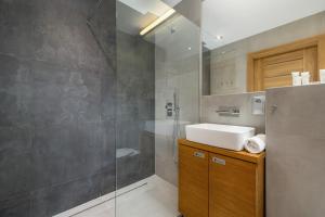a bathroom with a sink and a glass shower at Industrial Apartment Fredry with Parking by Renters in Krakow