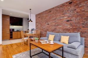 a living room with a couch and a brick wall at Industrial Apartment Fredry with Parking by Renters in Krakow