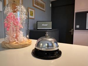 a silver pot on a table with a vase of flowers at Le 2 by Hotel Akena - Nantes Beaujoire, Porte de Sainte Luce in Sainte-Luce-sur-Loire
