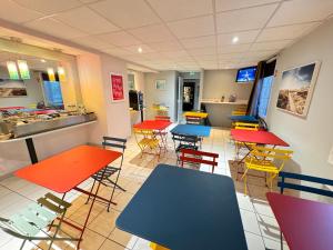 a restaurant with colorful tables and chairs in a cafeteria at Le 2 by Hotel Akena - Nantes Beaujoire, Porte de Sainte Luce in Sainte-Luce-sur-Loire
