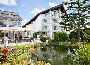 a hotel with a pond in front of a building at Hotel Derichsweiler Hof in Nümbrecht