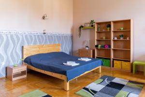 a bedroom with a blue bed and a book shelf at Tomka Apartman in Szeged