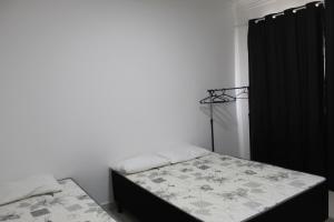 ein Schlafzimmer mit 2 Betten und einem schwarzen Vorhang in der Unterkunft Apt novissimo 3 quartos c elevador a 300m da orla Praia do Morro in Guarapari