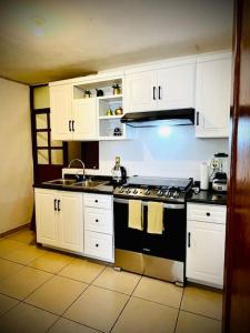 a kitchen with white cabinets and a stove top oven at Depa en el corazón de Guanajuato in Guanajuato
